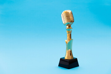 Golden microphone trophy on blue background