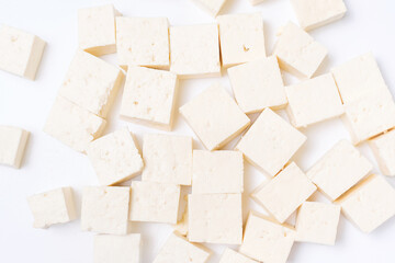 Cut tofu cubes on a white background close-up, top view.