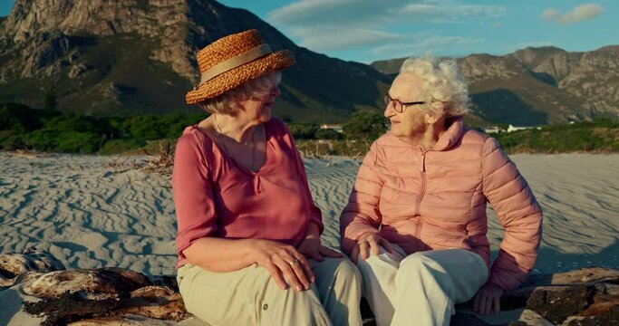 Senior women, friends and talk at beach on rocks, memory and conversation with reunion on holiday. Elderly lady, people and nature with smile, chat and relax with mountains, vacation and retirement