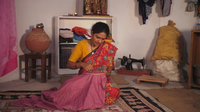 A village lady doing hand embroidery on a wooden frame - skill based work  lower middle class  earning hobby. A middle-aged Indian woman is using crafts in her free time - skilled lady  working hou...