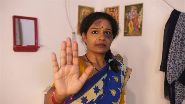 A middle-aged beaten-up woman with bruises and scars is signalling to stop violence - assault  physical injuries. A female victim of domestic violence is showing the sign to stop abusing - stop hur...