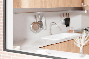 A bright beige-toned kitchen interior with sunlight 
coming through the window.