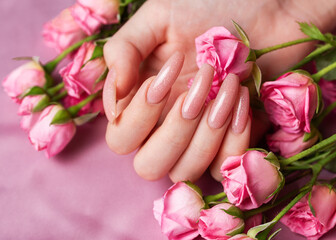 Female hands with pink nail design  hold pink roses