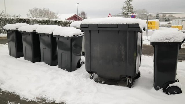 Garbage cans are standing in the snow in winter.