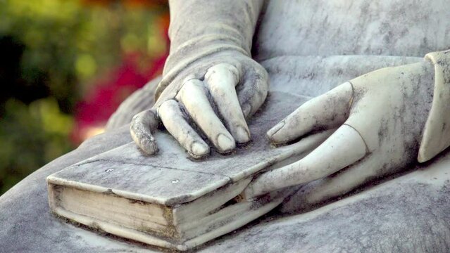 Close-up of a book and hands resting on a lap. Monument of Empress Elisabeth of Austria (Sissi monument) in Meran - Merano, South Tyrol, Italy