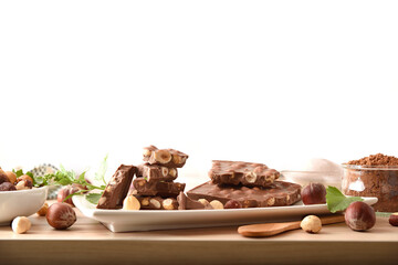 Chocolate with hazelnuts and ingredients on table white isolated background