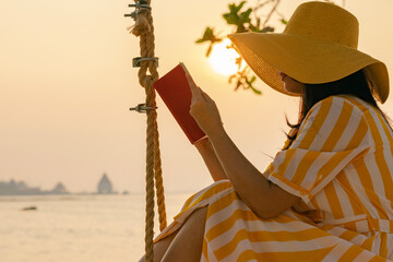 Outdoors lifestyle fashion portrait stunning asian woman enjoying on swing on the tropical island...