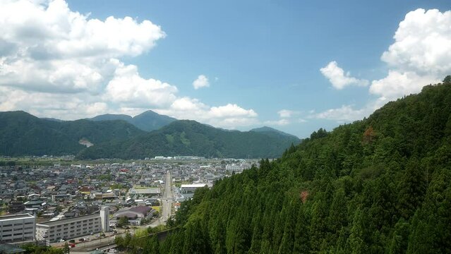 The city is surrounded by mountain, Green pine trees on the mountain with the bright sky in summer in summer at Katsuyama, Fukui,  Japan 