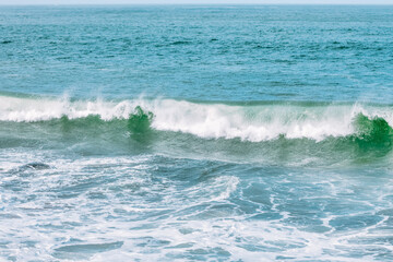 Fototapeta premium Wave splashes close-up. Crystal clear sea water hitting rock formations in the ocean in San Francisco Bay, blue water, pastel colors.