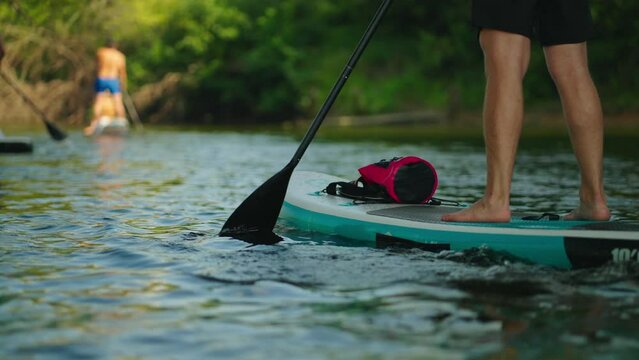 Trendy Kind Of Sport Standup Paddleboarding In River In Summer Day, Closeup View Of Male Legs