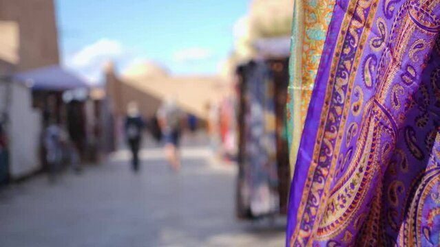 Silk scarves with traditional designs flutter in the wind on a shopping street in Khiva, Uzbekistan. Shopping streets of the ancient fortress Ichan-Kala.