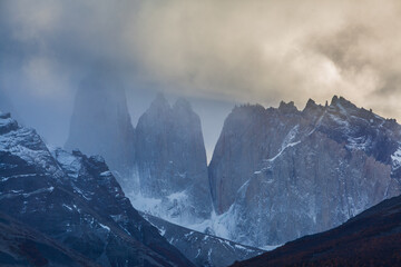 The jagged peaks of Torres del Paine disappearing in fog at sunset, Chile - obrazy, fototapety, plakaty