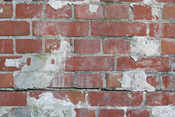 Weathered and worn old brick wall which has been repaired.