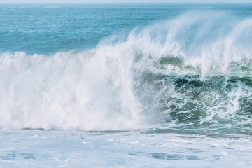 Wave splashes close-up. Crystal clear sea water hitting rock formations in the ocean in San Francisco Bay, blue water, pastel colors.
