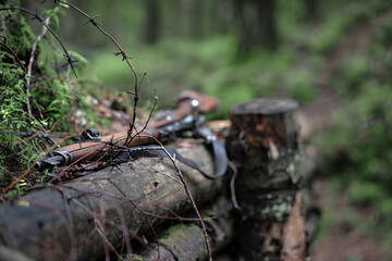 A rifle with a wooden butt is lying on the parapet of a wooden dugout in the forest. A shotgun from the Second World War. Military historical reconstruction.