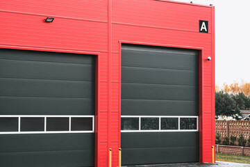 Industrial garage in black and red colors. A Bright Red Building with Modern Gray Garage Doors and a Security Camera Overlooking the Area