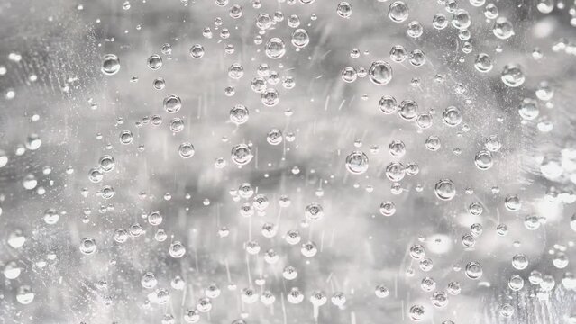 Sparkling water is poured into a glass beaker, blurred bubbles, light background