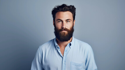 Obraz premium A bearded man dressed casually in a blue shirt shows off his good looks as he stands in a studio against a white backdrop 