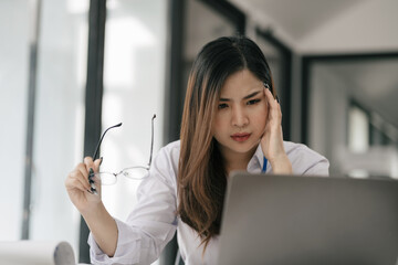 Businesswoman eyestrain fatigued from computer work, stressed women suffer from headache bad vision sight problem sit at office table using computer.