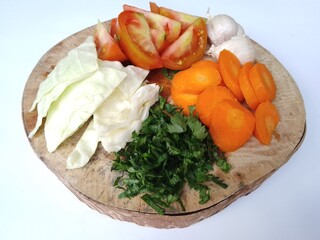 carrots, tomatoes, cabbage and celery that have been cut on a wooden cutting board