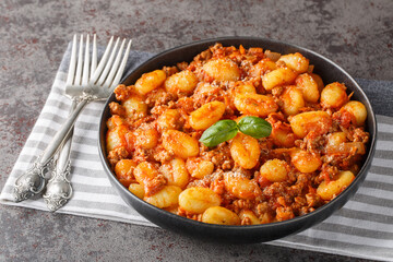 Italian potato gnocchi cooked with meat Bolognese sauce close-up in a plate on the table. Horizontal