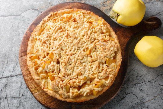 Crumble tart delicious combination of sweet, rich quince with streusel closeup on the wooden board on the table. Horizontal top view from above