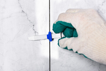 Tiler's hand installing leveling system tiles.