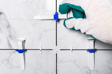 Tiler's hand installing leveling system tiles.