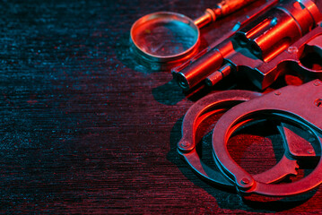 Police inspector handcuffs and gun on the black table flat lay background. Top view. Security....