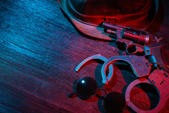 Police inspector handcuffs and gun on the black table flat lay background. Top view. Security. Secret service.