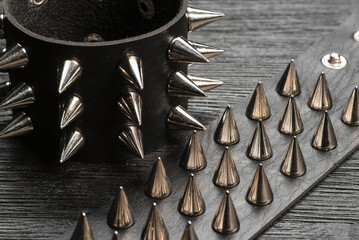 Black studded leather bracelet on the black wooden table background close up.