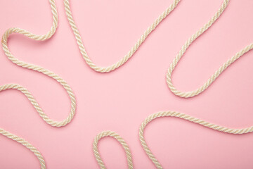 White wavy rope on pink background. Space for text