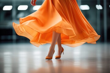 An elegant girl dances passionately in an orange dress, combining style and grace in a powerful display of rhythmic harmony.