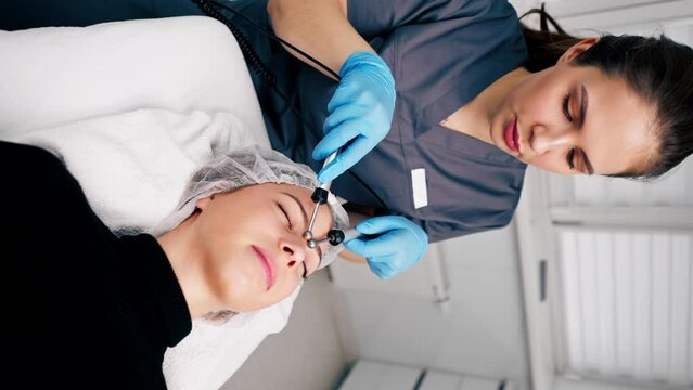  vertical video a beautician doctor massaging the skin of a client's face during a beauty and health cosmetic procedure