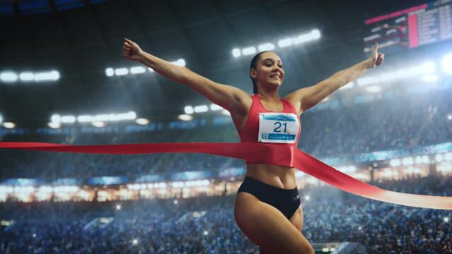 Strong Female Athlete Performing at Her Limit, Finishing a Competitive Run, Crossing the Finish Line with a Red Ribbon. Cinematic Sports Footage at a Crowded Arena with Spectators. Super Slow Motion