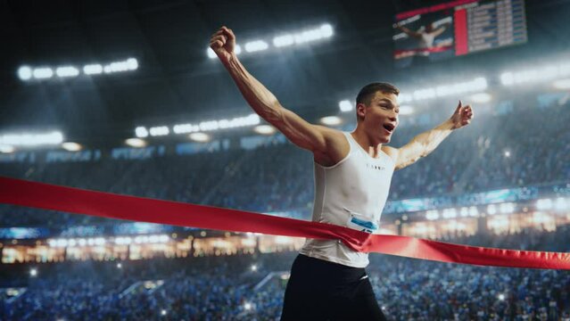 Fit Athlete Finishing a Sprint Run at a Crowded Arena with Cheering Spectators. Young Man Crossing the Finish Line with a Red Ribbon. Cinematic Super Slow Motion Sports Footage