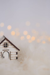 Miniature wooden house on white fur background with bokeh lights
