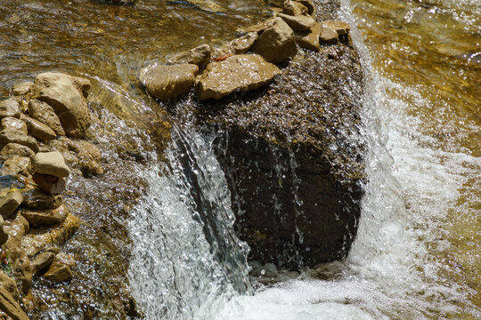 Rapids and waterfalls on the fast mountain river. Close-up of fast flowing water and stones. Olkhovka river in Kislovodsk national Park.