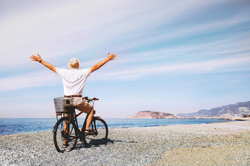 Turkey, Alanya. Carefree man standing by the sea opening his arms. Happy tourist with bicycle...