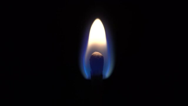 One match is burning on a black background, close-up, beautiful fire
