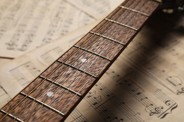 Guitar neck on paper sheets with music notes, closeup
