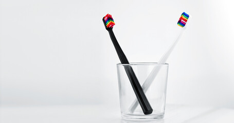 Stylish dental abacus in a glass cup. Black and White toothbrushs with multicolored bristles on...