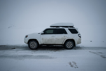 Fototapeta na wymiar Driving car on snowing high altitude mountain trail, China