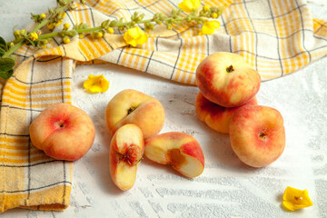 Halves and several whole saturn peaches or flat peach on white wooden background..