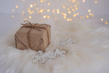 Christmas gift box on a white fur background with bokeh lights