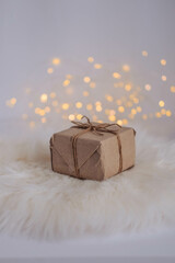 Christmas gift box on a white fur background with bokeh lights