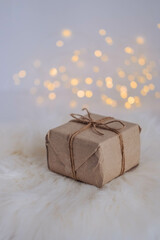 Christmas gift box on a white fur background with bokeh lights