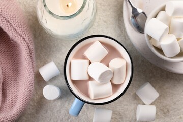 Cup of aromatic hot chocolate with marshmallows served on beige table, flat lay