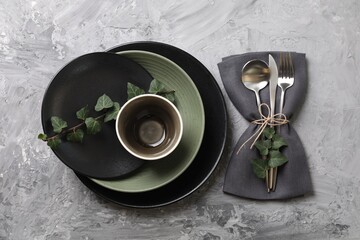 Stylish table setting. Dishes, cutlery, napkin and floral decor, top view