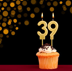 Birthday candle with cupcake - Number 39 on black background with out of focus lights